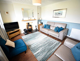 Self Catering Accommodation in Dornie living room with woodburning stove electric recliner seats and Smart TV with Freeview